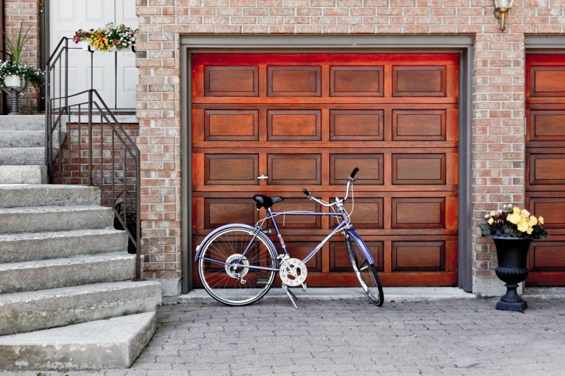 A remodeled, wood-paneled garage door with a bicycle leaning against it