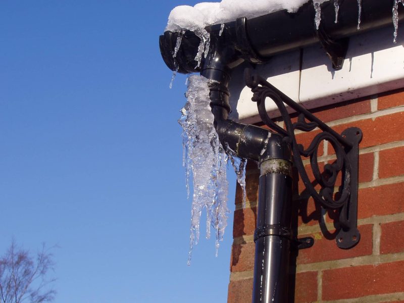 Close-up of a rain gutter with heavy icicles hanging from it