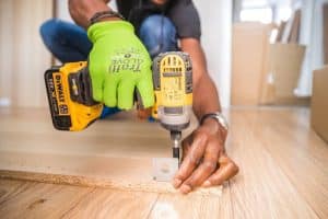 Close-up of a contractor’s hands as he prepared to drill into a plank of wood